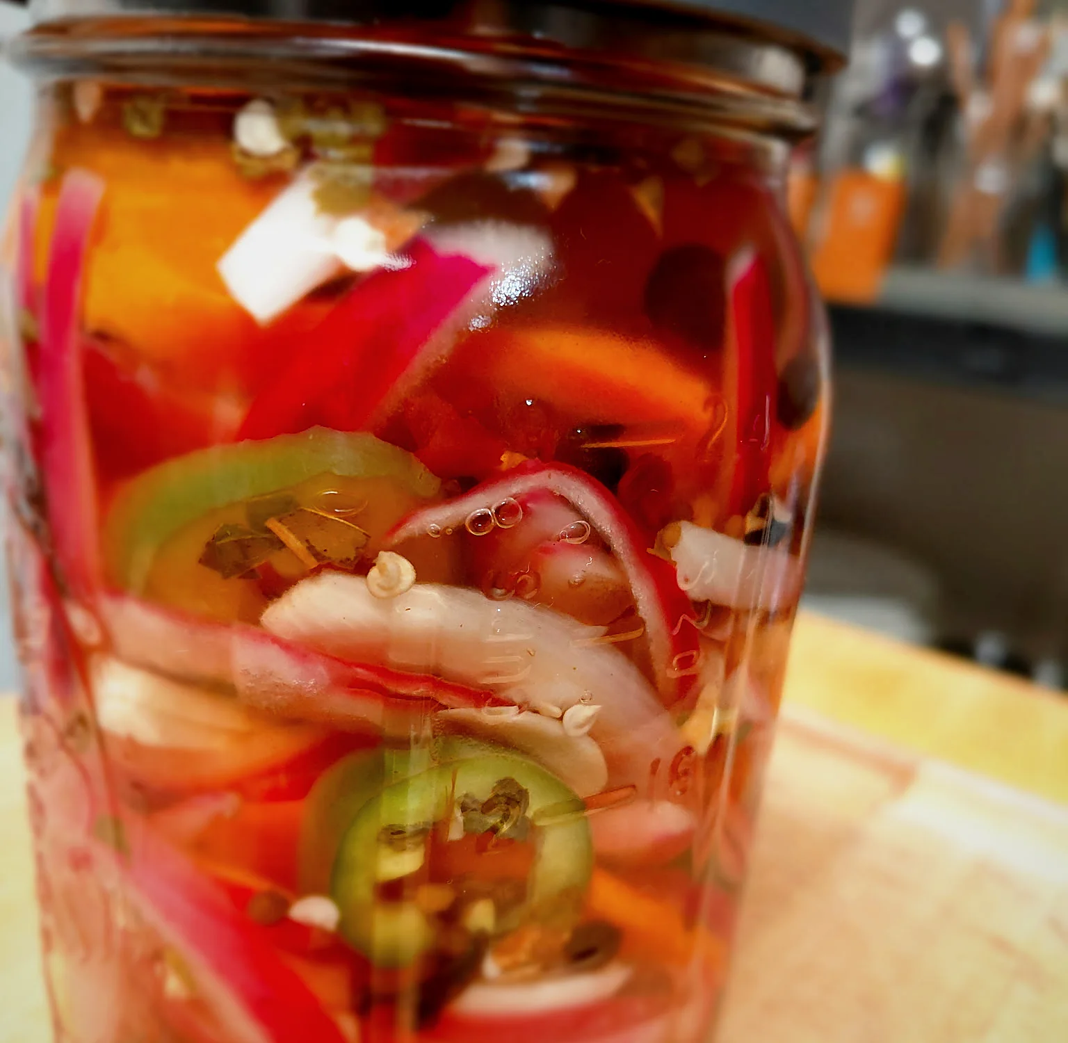 A jar of pickled vegetables on a wooden board